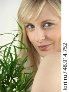 Blond woman holding green plant. Стоковое фото, агентство Ingram Publishing / Фотобанк Лори
