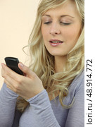 a blonde woman watching her cell phone. Стоковое фото, агентство Ingram Publishing / Фотобанк Лори