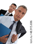 Portrait of a businessman with his assistant trailing behind him. Стоковое фото, агентство Ingram Publishing / Фотобанк Лори