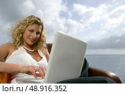 Blonde woman with a computer in front of the sea. Стоковое фото, агентство Ingram Publishing / Фотобанк Лори