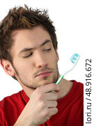 Young man looking at his toothbrush. Стоковое фото, агентство Ingram Publishing / Фотобанк Лори