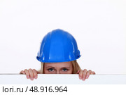 Tradeswoman peering over a low wall. Стоковое фото, агентство Ingram Publishing / Фотобанк Лори