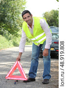 Man in fluorescent vest putting out a warning triangle by a breakdown. Стоковое фото, агентство Ingram Publishing / Фотобанк Лори