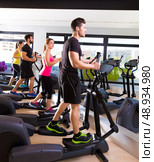 Aerobics elliptical walker trainer group at fitness gym workout. Стоковое фото, агентство Ingram Publishing / Фотобанк Лори