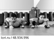 Dumbbells push-ups pushups couple at fitness gym workout. Стоковое фото, агентство Ingram Publishing / Фотобанк Лори