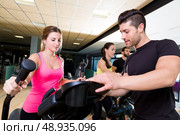 Aerobics elliptical walker trainer personal trainer man at fitness gym workout. Стоковое фото, агентство Ingram Publishing / Фотобанк Лори
