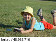 A young child is lying on the grass, holding a phone. Стоковое фото, фотограф K. / Фотобанк Лори