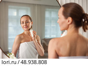 Middle-aged Woman Combats Skin Aging With Hand-Held Massager in Modern Home Setting. Стоковое фото, фотограф Aleksandr Golubev / Фотобанк Лори