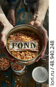 A person is holding a can of canned grubs, with the label partially obscured. There are other cans of grubs in the background. Стоковое AI-изображение, AI-художник Данила Большаков / Фотобанк Лори