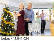 Happy mature woman enjoying impassioned merengue with male partner in dance room during celebration Christmas and New Year. Social dancing concept. Стоковое фото, фотограф Яков Филимонов / Фотобанк Лори