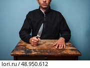 Dangerous man at table with a knife. Стоковое фото, агентство Ingram Publishing / Фотобанк Лори