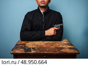 Dangerous man at table with a gun. Стоковое фото, агентство Ingram Publishing / Фотобанк Лори