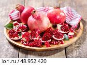 fresh pomegranates on wooden plate. Стоковое фото, агентство Ingram Publishing / Фотобанк Лори