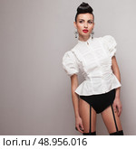 Trendy model in high shorts and white retro shirt on grey background. Стоковое фото, агентство Ingram Publishing / Фотобанк Лори