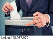 A white collar criminal is displaying obscene gesture while destroying evidence in shredder. Стоковое фото, агентство Ingram Publishing / Фотобанк Лори