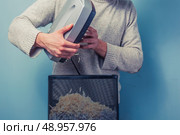 Young man is cleaning paper from a shredder. Стоковое фото, агентство Ingram Publishing / Фотобанк Лори