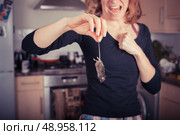 A disgusted young woman is holding a dead mouse by it’s tail in the kitchen. Стоковое фото, агентство Ingram Publishing / Фотобанк Лори