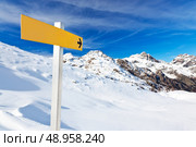 Yellow mountain guidepost along an alpine pathway over a snowy landscape in a clear winter day. Italian Alps, Val d’Aosta, Italy. Стоковое фото, агентство Ingram Publishing / Фотобанк Лори