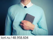 A young man is clutching a small notebook. Стоковое фото, агентство Ingram Publishing / Фотобанк Лори