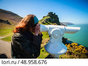 Young woman is looking through a telescope by the sea. Стоковое фото, агентство Ingram Publishing / Фотобанк Лори