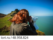 Young woman is looking through a telescope by the sea. Стоковое фото, агентство Ingram Publishing / Фотобанк Лори
