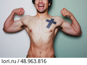 A young athletic man with a tattoo is flexing his muscles against a dual colored background. Стоковое фото, агентство Ingram Publishing / Фотобанк Лори