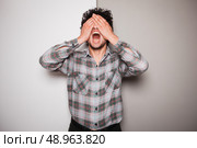 An upset young man is standing against a green and white background. Стоковое фото, агентство Ingram Publishing / Фотобанк Лори