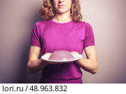 A young woman wearing a purple top is holding a plate with a pudding on it. Стоковое фото, агентство Ingram Publishing / Фотобанк Лори