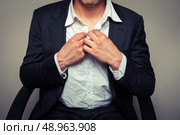 Young businessman sitting in office chair is buttoning his shirt. Стоковое фото, агентство Ingram Publishing / Фотобанк Лори