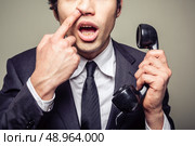Young incompetent businessman is on the phone and is picking his nose. Стоковое фото, агентство Ingram Publishing / Фотобанк Лори