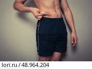 Fit young man pinching the fat on his stomach. Стоковое фото, агентство Ingram Publishing / Фотобанк Лори