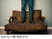 Man standing on sofa. Стоковое фото, агентство Ingram Publishing / Фотобанк Лори