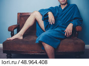 Young man in bathrobe sitting on a sofa. Стоковое фото, агентство Ingram Publishing / Фотобанк Лори