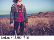 Woman standing in a field by the sea at sunset. Стоковое фото, агентство Ingram Publishing / Фотобанк Лори