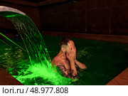 Submerged in Emerald Dreams, Youthful Man Seeks Solace Near Glowing Waterfall. Стоковое фото, фотограф Aleksandr Golubev / Фотобанк Лори
