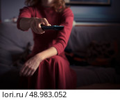 A young woman is siting on a sofa at home and is changing TV channels with a remote control. Стоковое фото, агентство Ingram Publishing / Фотобанк Лори