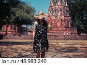 A young woman is drinking juice from a coconut near the ruins of an ancient buddhist temple. Стоковое фото, агентство Ingram Publishing / Фотобанк Лори