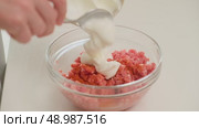 Close-up of a hand adding sour cream to a bowl of raw ground meat, preparing ingredients for a home-cooked meal. Стоковое видео, видеограф Андрей Журавлев / Фотобанк Лори