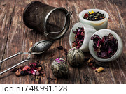 tea strainer and different varieties of tea leaves on wooden background.The toned image. Стоковое фото, агентство Ingram Publishing / Фотобанк Лори
