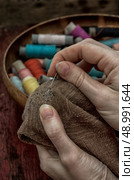 hands in the process stepania holey socks on the background of sewing thread. Стоковое фото, агентство Ingram Publishing / Фотобанк Лори