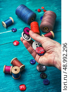hand dressmaker with wooden buttons on turquoise background. working tool dressmaker. Стоковое фото, агентство Ingram Publishing / Фотобанк Лори