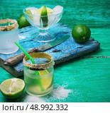 glass alcoholic drink and lime fruits on wooden texture.Selective focus. alcoholic cocktail with additions of lime. Стоковое фото, агентство Ingram Publishing / Фотобанк Лори