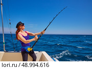 Beautiful woman girl fishing rod trolling in saltwater in a boat trolling. Стоковое фото, агентство Ingram Publishing / Фотобанк Лори