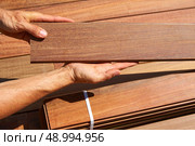 Ipe decking installation with carpenter hands holding tropical wood slats. Стоковое фото, агентство Ingram Publishing / Фотобанк Лори