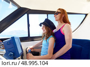Kid girl pretending be a captain sailor cap with her mother in boat indoor. Стоковое фото, агентство Ingram Publishing / Фотобанк Лори