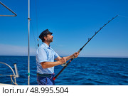 Beard sailor man fishing rod trolling in saltwater in a boat trolling with captain cap. Стоковое фото, агентство Ingram Publishing / Фотобанк Лори