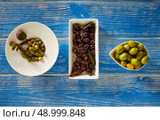 Mediterranean pickles tapas black olives and capers on blue wood table. Стоковое фото, агентство Ingram Publishing / Фотобанк Лори