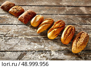 Breads varied in a row on rustic wood table with wheat flour. Стоковое фото, агентство Ingram Publishing / Фотобанк Лори