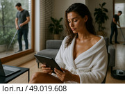 Утро в стиле "hygge": женщина в халате с планшетом, уборка дома на фоне, умный дом, помощники по дому. Стоковое AI-изображение, AI-художник Оксана Хорватич / Фотобанк Лори