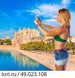 Blond tourist in Mallorca taking photos of Palma Cathedral photomount. Стоковое фото, агентство Ingram Publishing / Фотобанк Лори